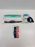 Group shot of smartwatch, digital watch, teal band, navy/pink straps, and Logiix micro-USB cable