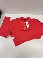 Full view of coral long-sleeve henley laid flat