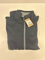 Folded jacket showing tag and front zipper