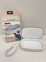 Open Vie Ol sanitizer showing white interior beside retail box and USB cable