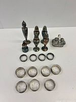 Group shot showing all items: six tall shakers, cruet caddy with glass bottles, eight napkin rings