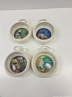 Overview of four ceramic bowls showing handles and interior advertising decals
