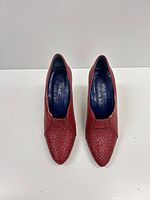 Top view of both red pumps showing woven toe detail and blue branded insoles