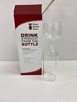 wine bottle glass beside retail box front showing branding and capacity