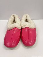 Top view of slippers showing pink leather exterior and white faux shearling lining