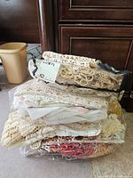 Stack of three clear zip bags filled with crochet and lace linens