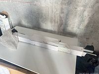 Long aluminum roof rack bar inside white sleeve packaging on table