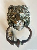 front view of cast metal lion head door knocker with ring and hardware