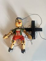 Full view of wooden Pinocchio marionette with control bar and strings