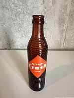 Front view showing amber ribbed bottle and orange diamond label