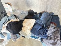 Pile of assorted denim jeans, shorts and jackets on table