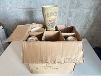 Box with multiple beige ceramic pots in dividers
