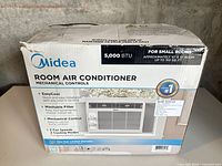 Front of sealed box showing Midea branding, 5,000 BTU rating and product image