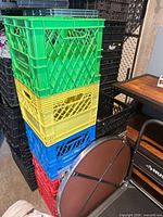 Stack of multicolour milk crates with black crates behind