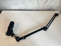 Microphone attached to full length of black boom arm on white surface