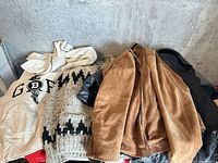 Pile showing all four garments: white hoodie, grey wool sweater, brown suede jacket, black leather jacket