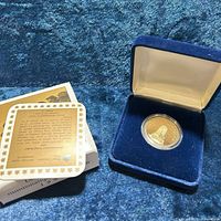 coin in capsule inside blue velvet case beside COA and outer sleeve