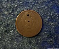Obverse of coin showing faint design and holes