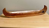 Full view of wooden canoe on tabletop showing overall shape and finish