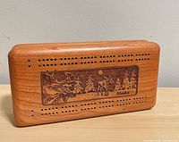 Front view of wooden cribbage board showing engraving and scoring holes