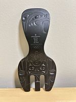 Front view of black plastic salad fork showing Indigenous carving details, Inukshuk, Olympic rings, overall condition