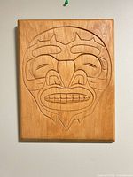 Front view of carved wood plaque showing full Indigenous motif