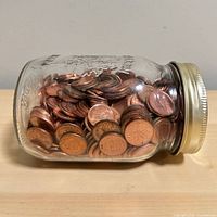 Side view of jar lying on its side showing numerous copper Canadian pennies
