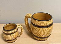 Front view of both barrel-pattern ceramic mugs, showing size difference