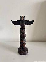 Front view of resin totem pole showing stacked figures and Alaska base