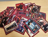 Assortment of red-border Star Trek TNG cards spread on table
