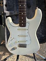 Front view of white left-hand Fender Stratocaster showing pickups, controls and rosewood fretboard