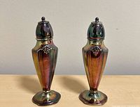 Front view of both silver-plated shakers on wood surface
