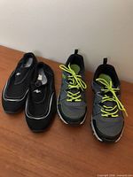 Two pairs of shoes side by side: black Athletic Works water shoes and grey Fila athletic shoes