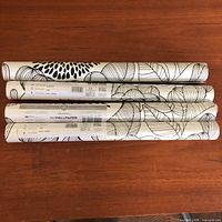 Four wallpaper rolls on table showing labels and pattern