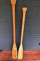 Full view of both wooden paddles leaning against wall