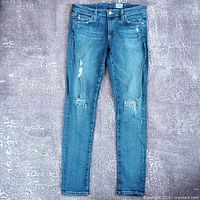 Full front view of jeans displaying overall style, wash and distressing