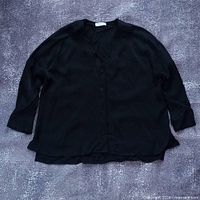 Full view of black button-up blouse laid flat