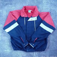 Front view of blue/red/white colour-block jacket showing closure and design