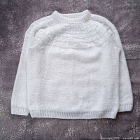 Full view of white hand-knit sweater front, showing overall design