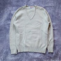 Full view of cream wool V-neck sweater laid flat