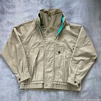 Full view of front of tan utility jacket laid flat