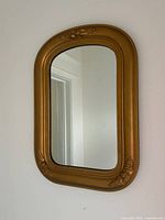 Front view of gold arched wooden mirror on wall