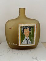 Front view of satin amber pillow-shape art glass bottle showing Modigliani-style portrait and signature