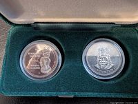 Two commemorative coins in green presentation case