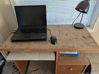 Top view of wood desk with tan tile surface, laptop and lamp on top