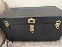 Closed black steamer trunk showing brass hardware and overall exterior condition