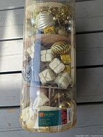 Sealed clear cylinder with assorted gold and white ornaments