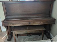 front view of upright piano with bench underneath