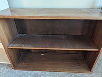 Front view of brown bookcase showing interior shelf and wear