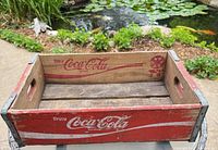 Overall view of red Coca-Cola crate by pond